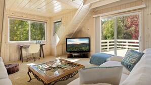 A cozy living room with a wooden ceiling, a television, a sofa, a coffee table, and a desk with a chair. - Lakefront, Spa, Pool Table, King Beds, Fireplace, Deck, Grill, Private Dock (Big Bear Lake)