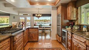 A spacious kitchen with wooden cabinets, a large island, and a view of a lake. - Lakefront, Spa, Pool Table, King Beds, Fireplace, Deck, Grill, Private Dock (Big Bear Lake)