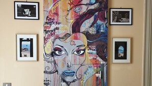 Una sala de estar moderna con un cuadro abstracto grande en la pared, una mesa de centro de madera y un sofá minimalista.
