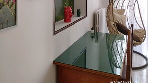 Una habitación con una mesa de vidrio, un sillón colgante e impresiones botánicas enmarcadas en la pared.