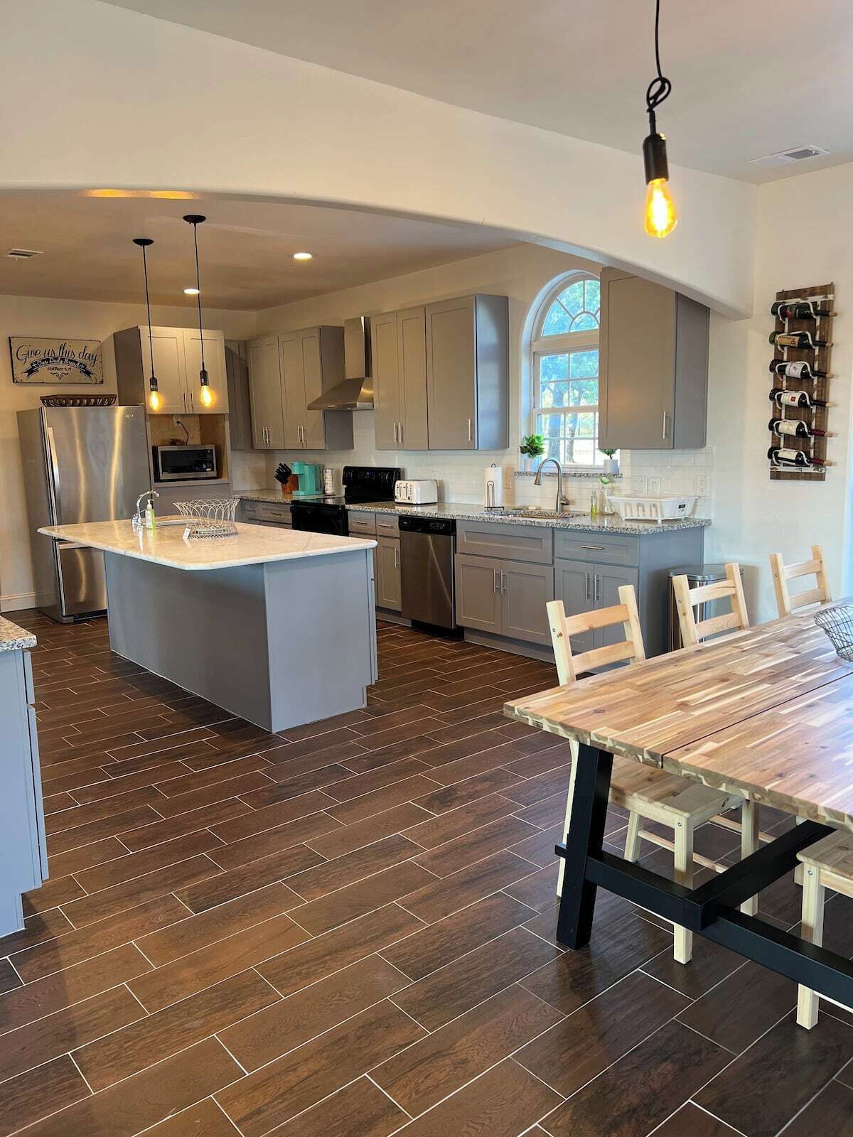 A modern kitchen with a central island, stainless steel appliances, and a dining area with a wooden table and chairs.