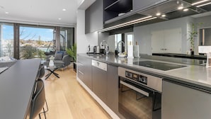 A modern kitchen with a large island, built-in appliances, and a view of the outdoors. - Light & relaxing on city fringe (Auckland)