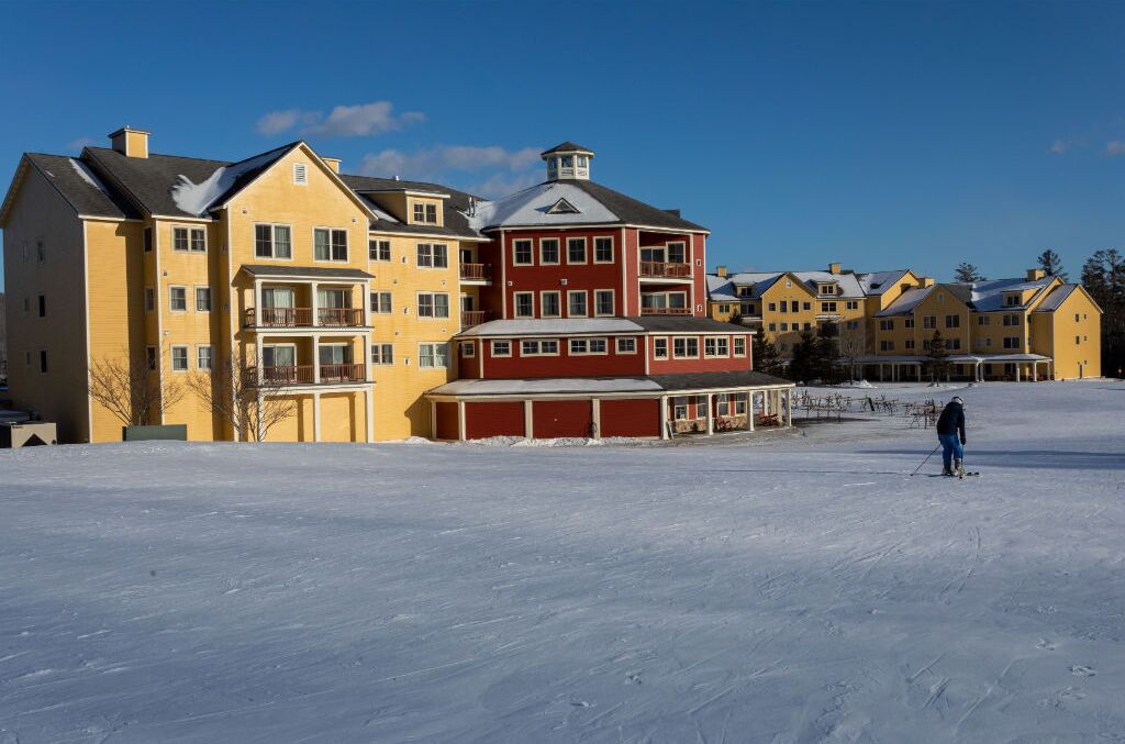 A snow-covered area with a row of multi-story buildings, including a red and yellow structure with balconies.