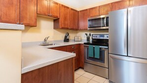 A kitchen with wooden cabinets, a stainless steel refrigerator, a microwave, an oven, and a sink. - Okemo | 1BR + Loft Condo + Close to All Amenities (Ludlow)