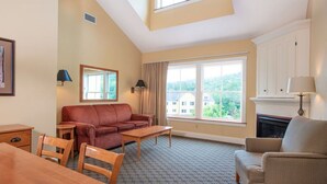A cozy living room with a sofa, armchairs, a coffee table, and a fireplace. - Okemo | 1BR + Loft Condo + Close to All Amenities (Ludlow)