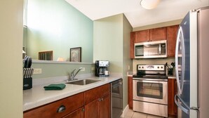 A kitchen with wooden cabinets, stainless steel appliances, and a countertop with a coffee maker. - Okemo | 2BR + Exec Loft Condo w/ Washer & Dryer (Ludlow)