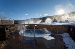Relax in a hot tub surrounded by a brick-paved area and scenic views.