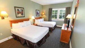 Ein Hotelzimmer mit zwei Betten, einem Schreibtisch, einem Spiegel und zwei Wandlampen.
