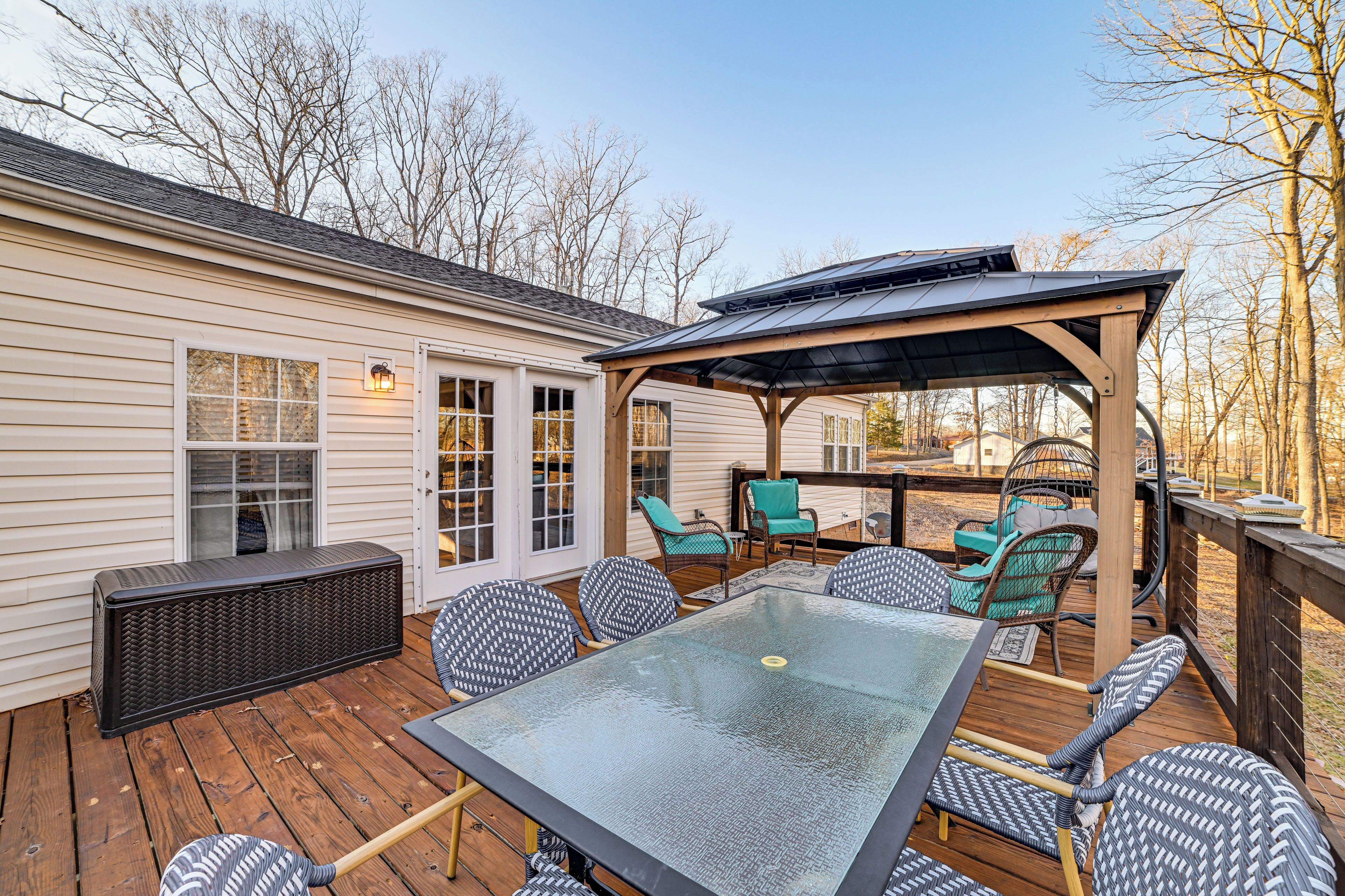 A covered outdoor patio with a glass table and wicker chairs, a built-in heater, and a pergola with a roof.