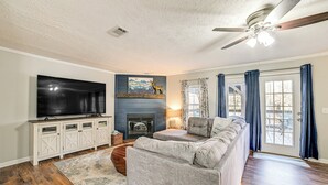A living room with a flat-screen TV, a fireplace, a sofa, and a ceiling fan. - Benton Vacation Rental Near Kentucky Lake! (Benton)
