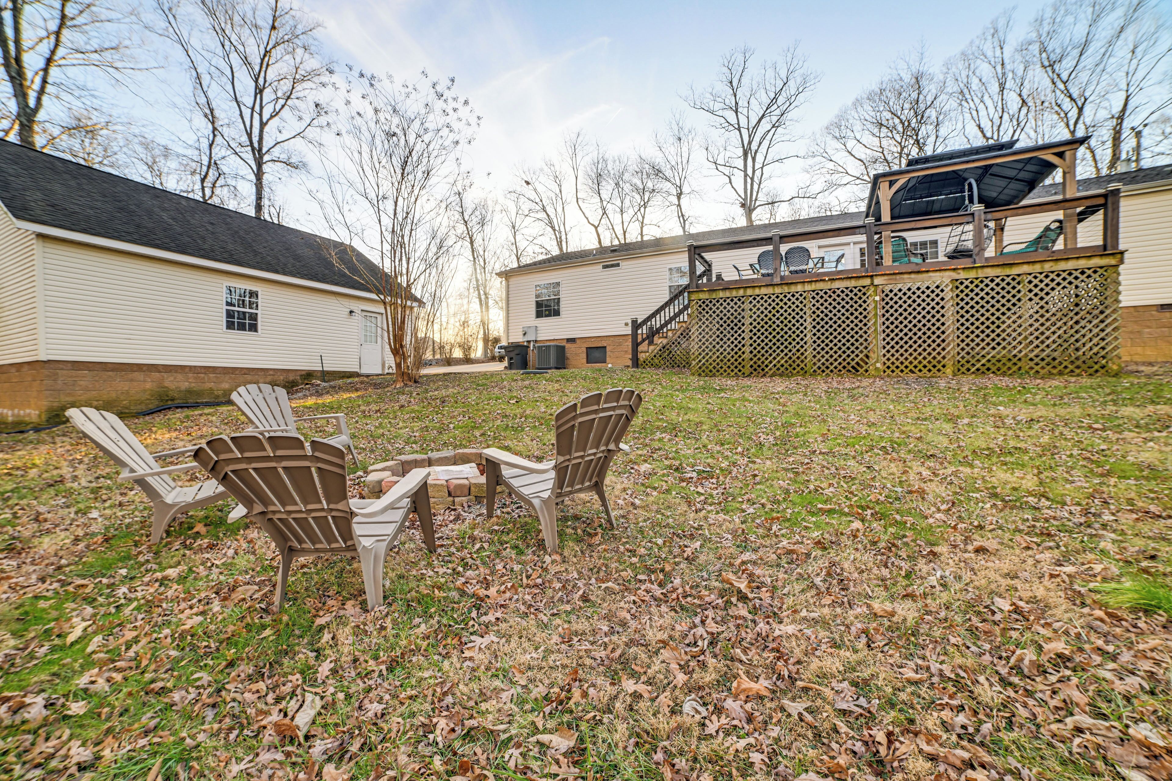 A backyard with Adirondack chairs, a barbecue area, and a covered patio.