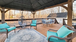 A covered outdoor deck with wicker furniture, a patterned rug, and a view of the surrounding area. - Benton Vacation Rental Near Kentucky Lake! (Benton)