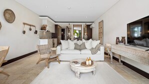 A spacious living room with a white sofa, a wooden chair, and a coffee table. - Coastal Luxe at Santai 229 (Tweed)