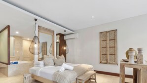 A spacious bedroom with a large bed, a wooden bench, a small table, and a decorative wall panel. - Coastal Luxe at Santai 229 (Tweed)