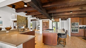 A spacious kitchen with a large island, wooden cabinets, and modern appliances.