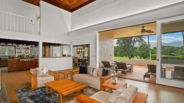 A spacious living area with a kitchen, a dining area, and a patio with outdoor seating.