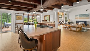 A spacious kitchen with a large island, wooden beams, and pendant lighting.