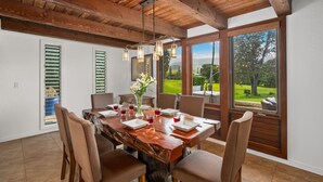 A dining area with a large wooden table, chairs, and a view of the outdoors.