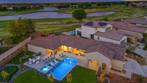 A residential area with a swimming pool, multiple houses, and a view of a lake and mountains in the background. - Palmer Retreat: #260334 3 BR, Pool, Spa, Foosball! (La Quinta)