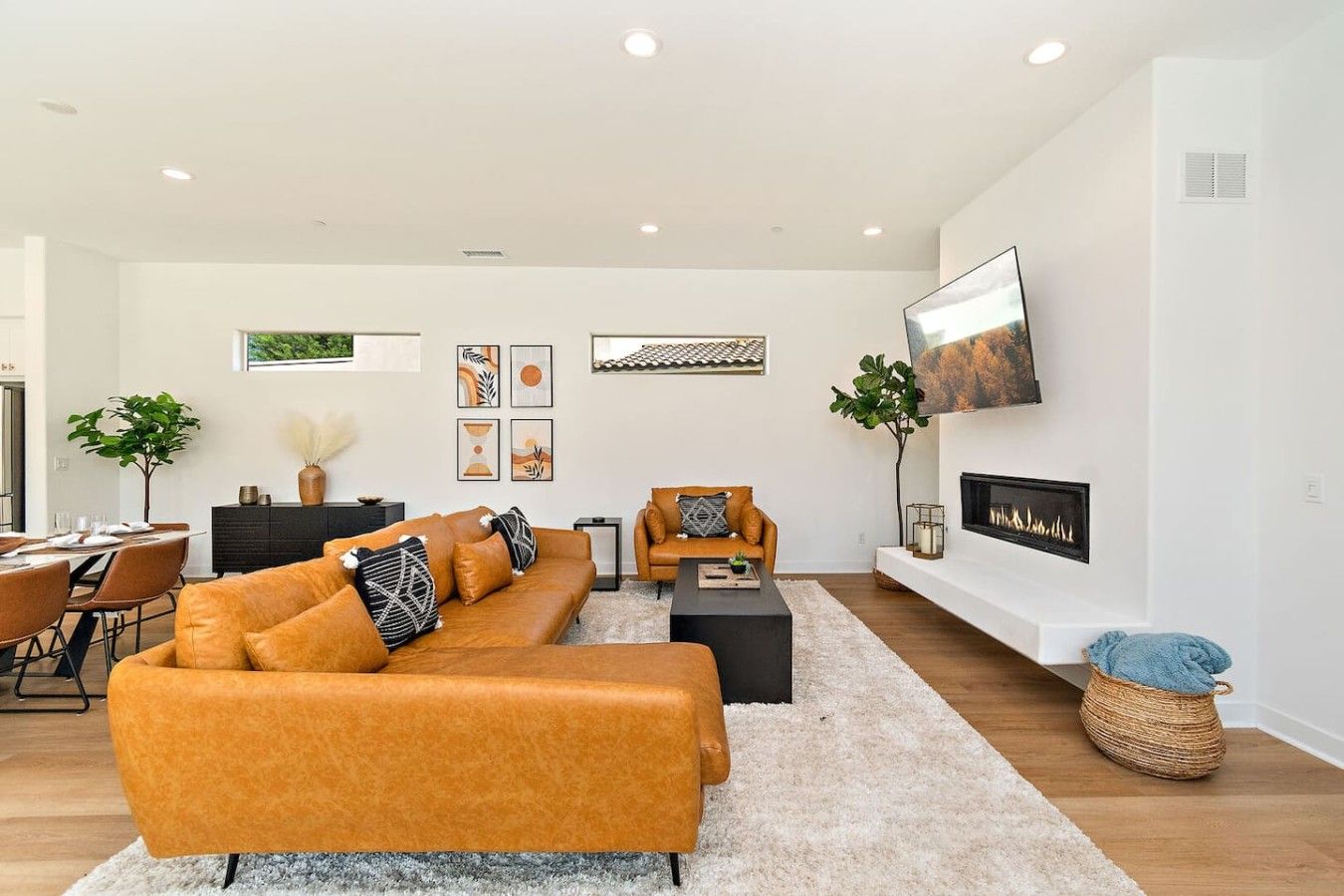 A modern living room with a sectional sofa, a coffee table, a fireplace, and a television mounted on the wall.