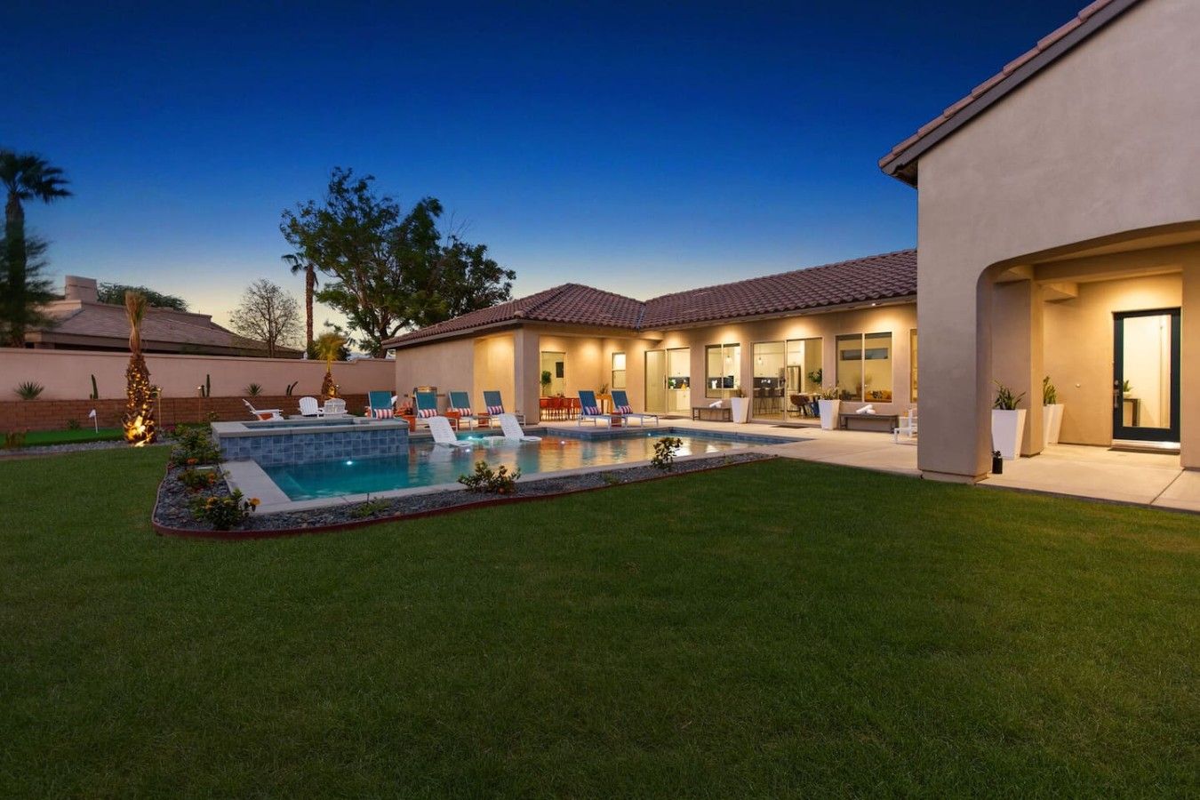 A residential property with a swimming pool, outdoor seating, and a well-maintained lawn.