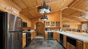 A spacious kitchen with wooden cabinets, a stainless steel refrigerator, and a central island. - Waterview Lodge. New Addition. Spa. Lake views. (Big Bear Lake)