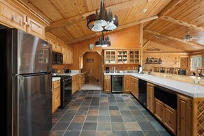 Une cuisine spacieuse dotée de meubles en bois, d’un réfrigérateur en acier inoxydable et d’un îlot central.