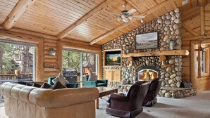A log cabin interior with a stone fireplace, leather furniture, and large windows. - Waterview Lodge. New Addition. Spa. Lake views. (Big Bear Lake)