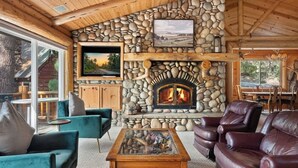 A cozy interior with a stone fireplace, comfortable seating, and a television. - Waterview Lodge. New Addition. Spa. Lake views. (Big Bear Lake)