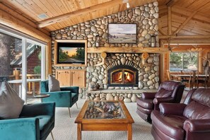 A cozy interior with a stone fireplace, comfortable seating, and a television. - Waterview Lodge. New Addition. Spa. Lake views. (Big Bear Lake)
