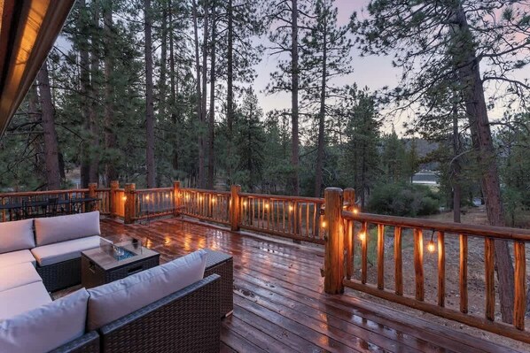 A wooden deck with outdoor seating and a railing.