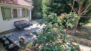 A small house with a patio area featuring a table and chairs, surrounded by greenery and a tree. - Studio detached with garden (Medulin)