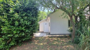 A small, single-story building with a white door and a small porch. - Studio detached with garden (Medulin)