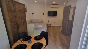 A compact room with a bed, a TV, and a dining area with a table and chairs. - Studio detached with garden (Medulin)