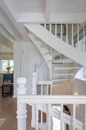 A white staircase with a balustrade, leading to an upper floor.