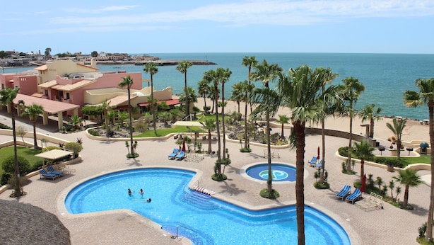 Ein Resort mit einem großen Schwimmbad, Palmen und Blick auf den Ozean.