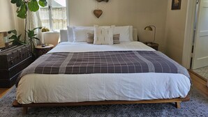 A neatly made bed with a patterned bedspread, a bedside lamp, and a decorative wall piece.