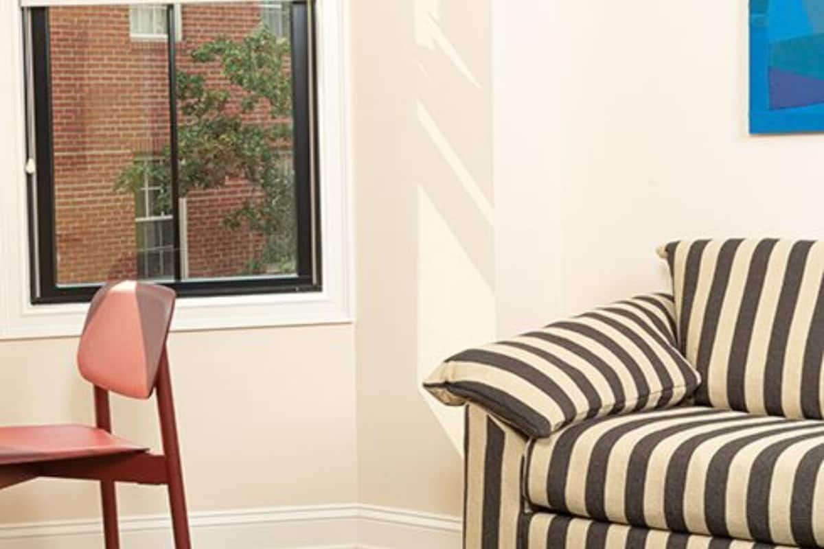 A room with a window, a sofa, a chair, and a table.