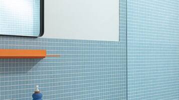 A bathroom with a white sink, blue tiles, a white toilet, and a shower head.