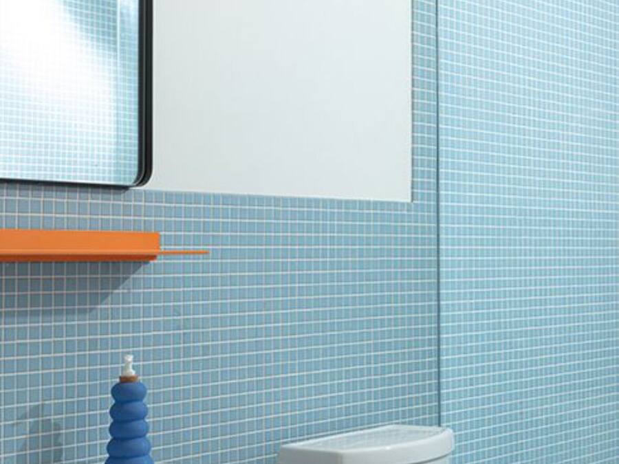 A bathroom with a white sink, blue tiles, a white toilet, and a shower head.