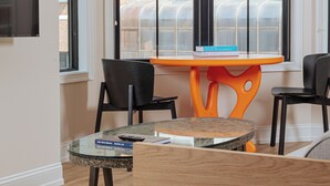 A room with a round glass table, two black chairs, a wooden bench, a green rug with circular cutouts, and a hanging pendant light. - YOWIE (Hotel & Shop) (Philadelphia)