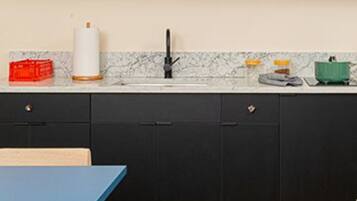 A modern kitchen with black cabinets, a marble backsplash, and a wooden floor.