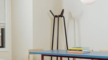 Un comedor moderno con una mesa azul, sillas de madera, una mesita auxiliar de madera oscura e iluminación colgante.
