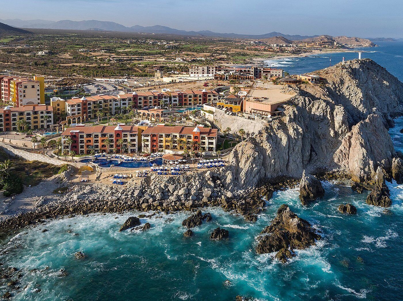 A coastal resort with multiple buildings, a rocky shoreline, and a view of the ocean.