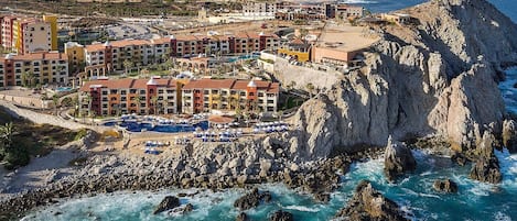 Un complejo turístico costero con varias edificaciones, un litoral rocoso y vistas al océano.