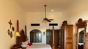 A bedroom with a bed, a nightstand, a dresser, a mirror, and a ceiling fan.