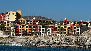 A coastal hotel with colorful buildings, a rocky shoreline, and a view of the sea.