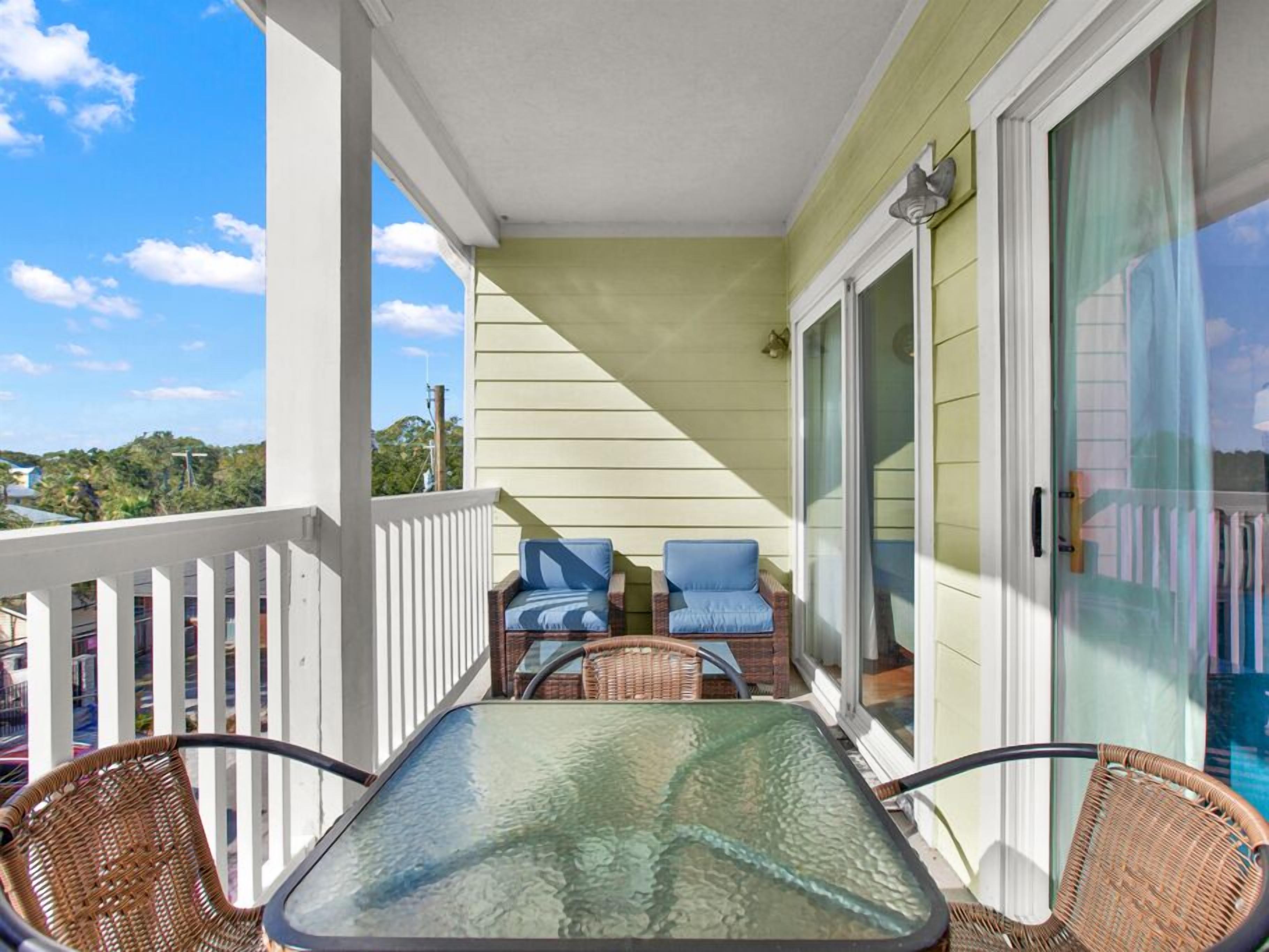 Een balkon met rieten stoelen, een glazen tafel en uitzicht op de oceaan.