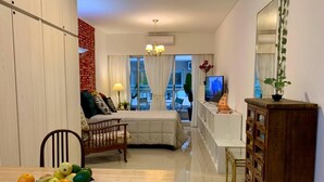 A modern hotel room with a bed, a TV, a dining area with a fruit bowl, and a view of the city. - San Telmo- Luxury and Comfort in Temporary Rental (Buenos Aires)
