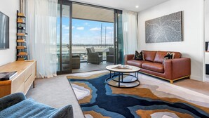 A modern living room with a sofa, coffee table, and a view of the outdoors through a sliding glass door.
